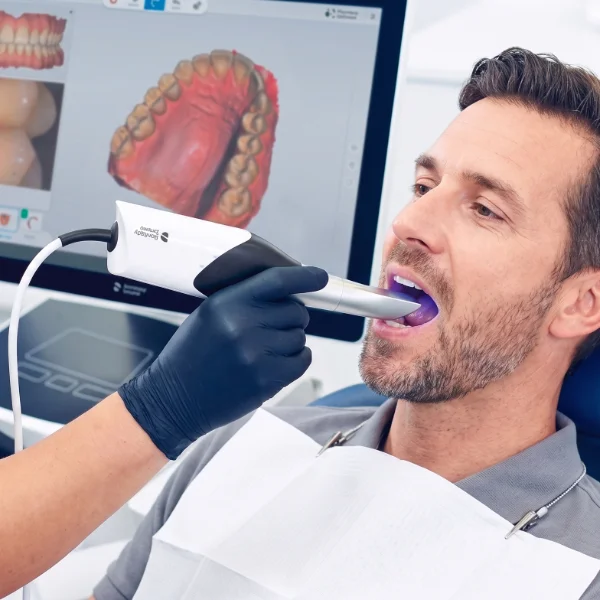 adult male getting teeth scaned with a digital scanner at dentist office.