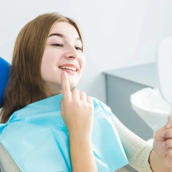 Teenager admiring her nice smile a dentist office