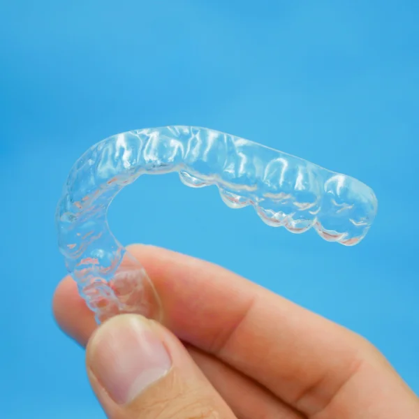 photo of a hand holding transparent clear aligners